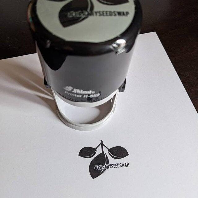picture of a round self-inking stamp and white paper with black ink impression