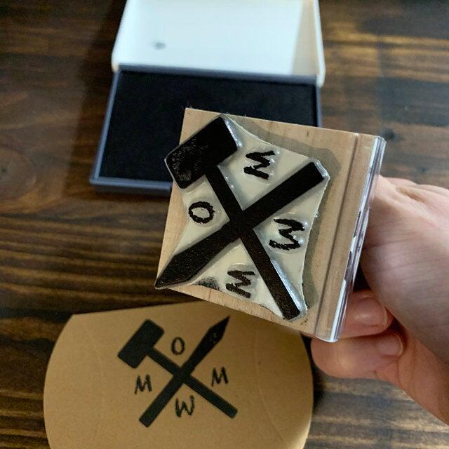 picture of a wood handle rubber stamp and brown paper with black ink impression