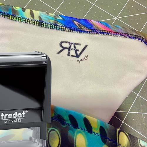 picture of a Trodat fabric stamp in front of a bathing suit with a black ink impression